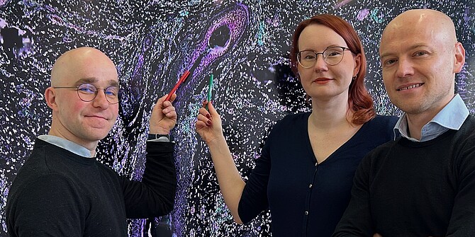 Mischa Selig, Jana Ihlow (zentral) und Livius Penter (rechts) vor einem Zellbild 