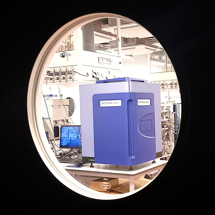 Blick in durch ein Labortürfenster auf ein Biomark qPCR Gerät