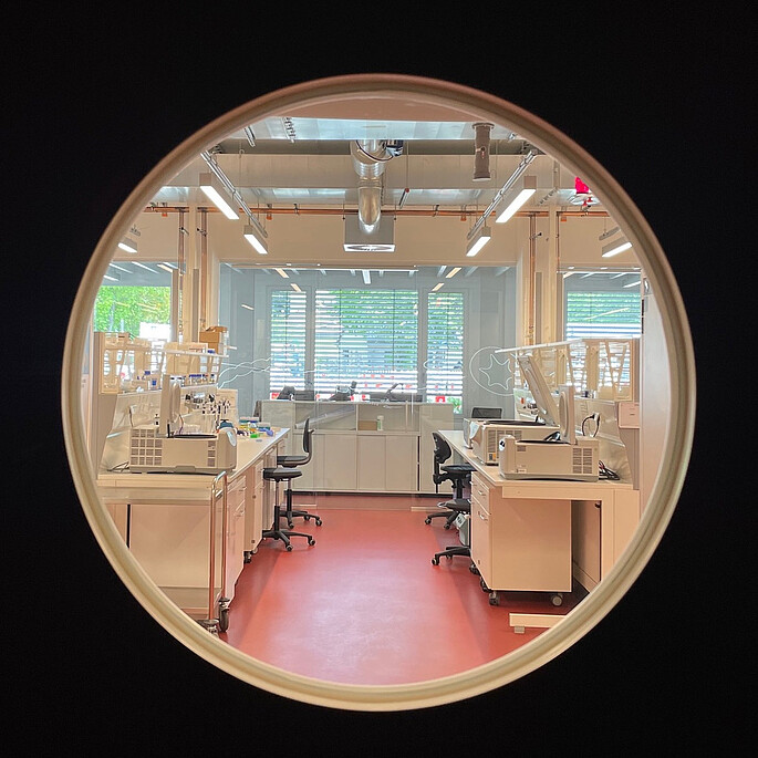 Blick in durch ein Labortürfenster in einen Laborbereich