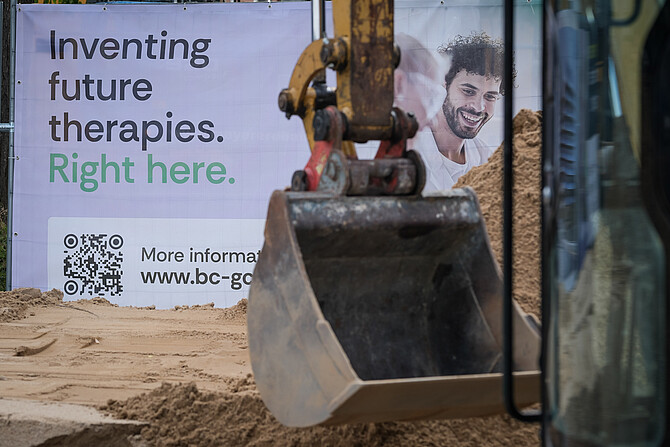 Eine Baggerschaufel vor einem Banner mit der Aufschrift Inventing future therapies right here.